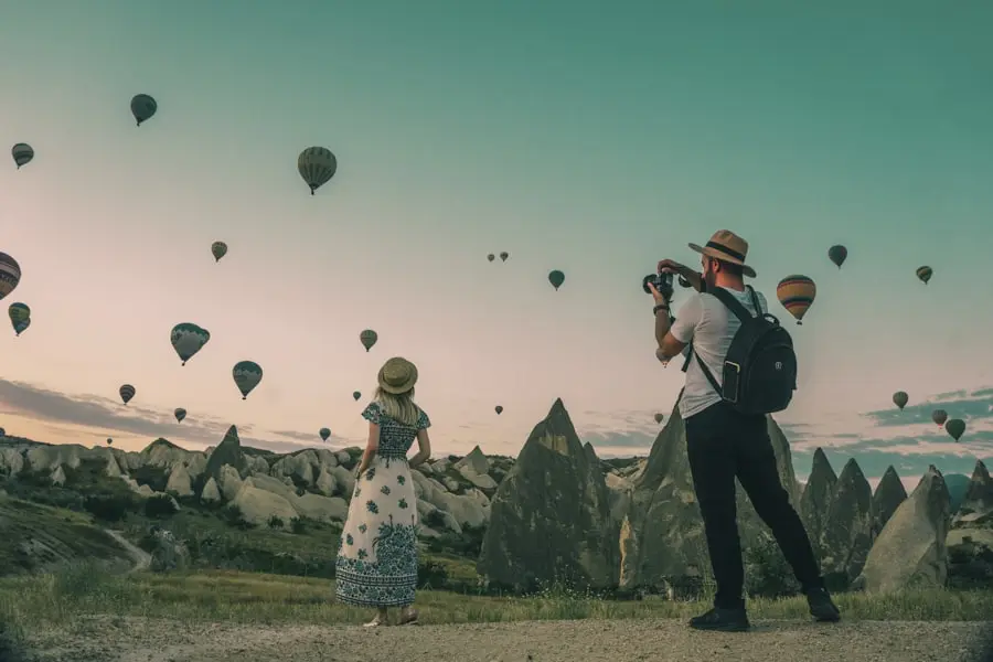 Dos personas fotografiando globos aerostáticos al amanecer